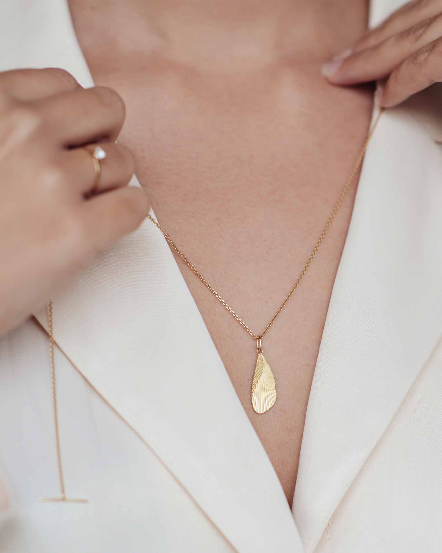 Frau hält sich eine Gold Kette mit Anhänger vor ihr dekolte und schaut ob diese gerissen ist oder ganz