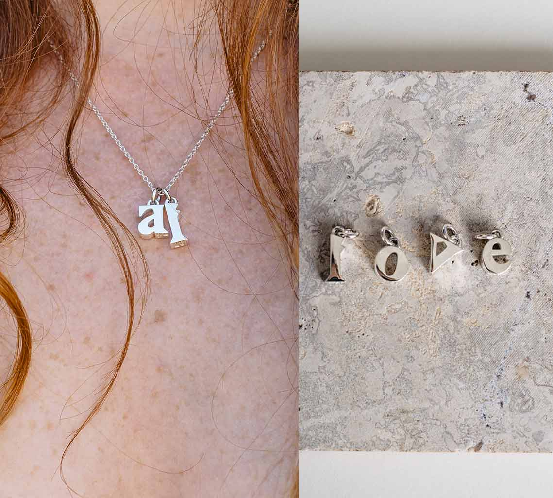 Dekolte mit 2 Buchstabenanhänger aus Silber an Kette und daneben love mit den Buchstaben Anhängern gelegt