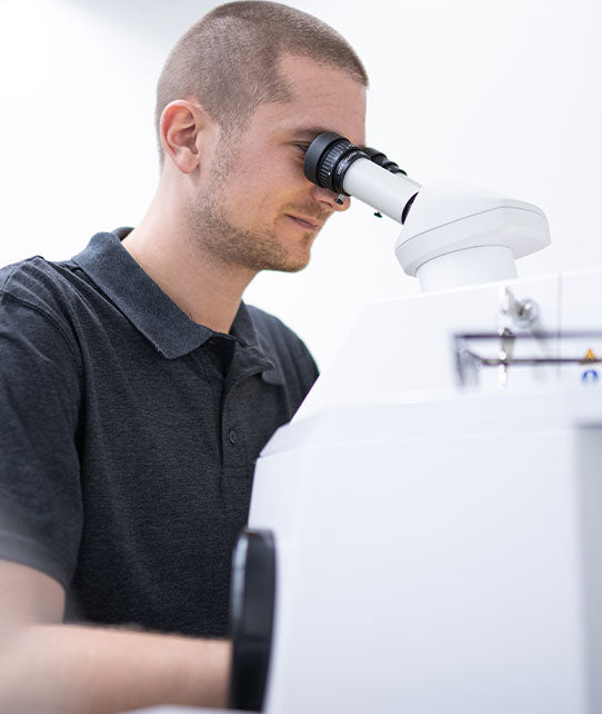 Schmuck Graveur arbeitet sitzen unter Mikroskop an einer Gravur