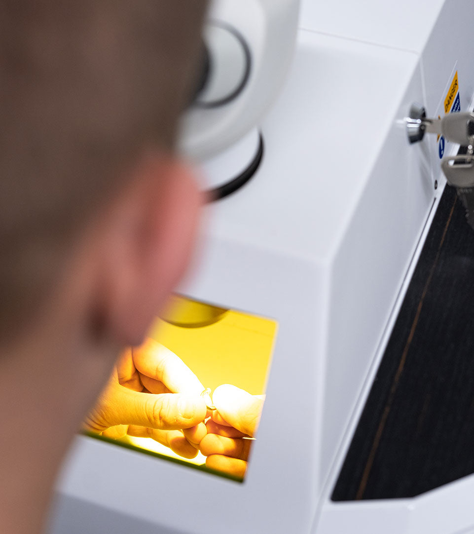 Die Hände des Graveurs wie er in einem Laser arbeitet