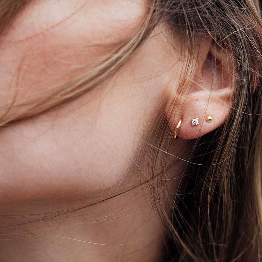 Frau trägt Earcandy drei mini Ohrstecker Piercings