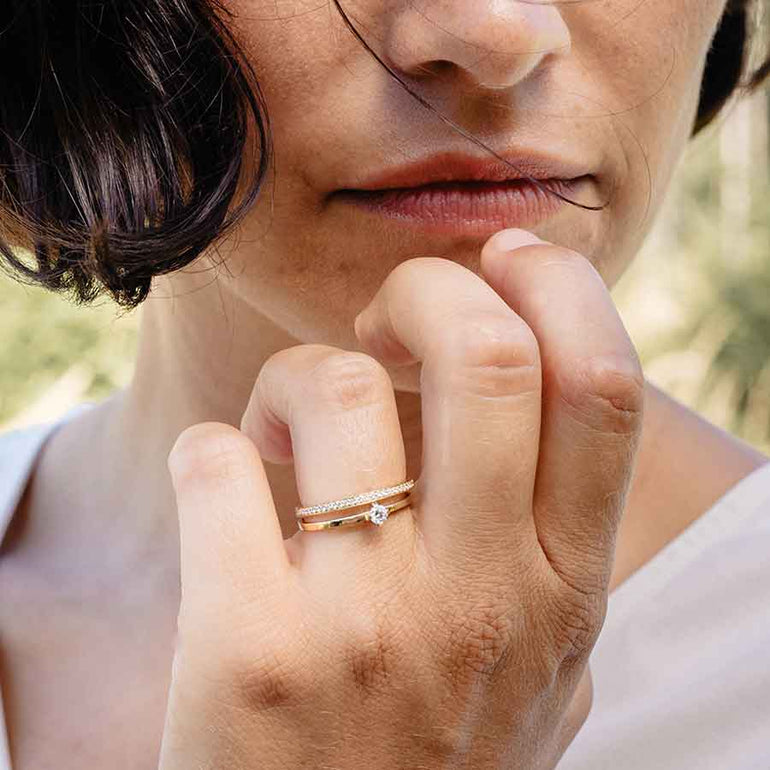 Goldener Solitärring mit vorgestecktem Eternity Ring am Finger