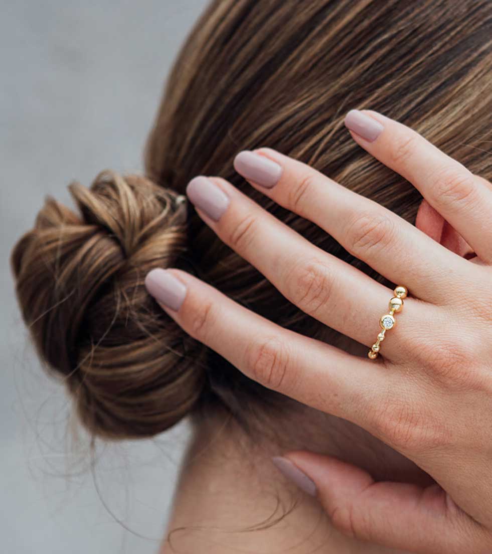 Hand an elgeanter Haarfrisur mit Goldenem Kugelring und Diamant