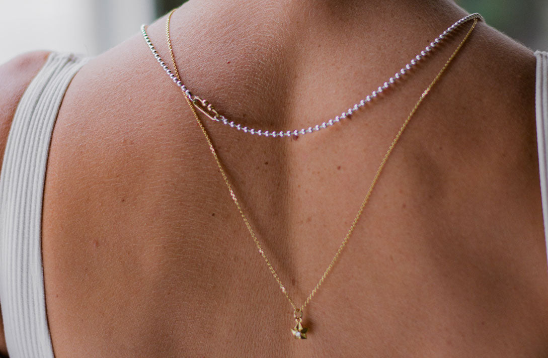 Nachhaltige Bicolor Ketten in Silber und Gelbgold von Maren Jewellery am freien Rücken eines Models