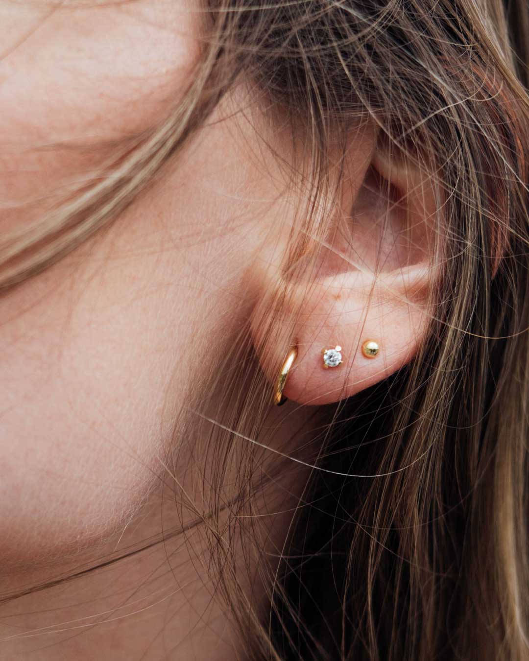 Detailaufnahme zeigt das Ohr einer Frau, das mit nachhaltigen Ohrsteckern und Ohrringen von Maren Jewellery geschmückt ist