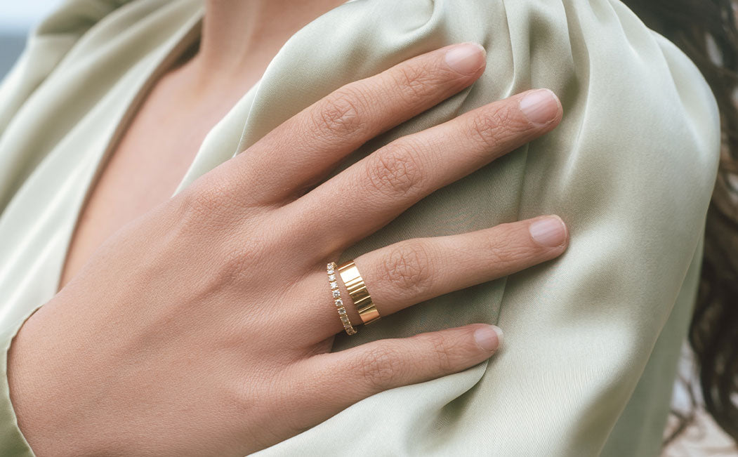 Nahaufnahme der Hand eines Models, die anihrem Ringfinger einen Ehering und Vorsteckring aus recyceltem Gold von Maren Jewellery trägt
