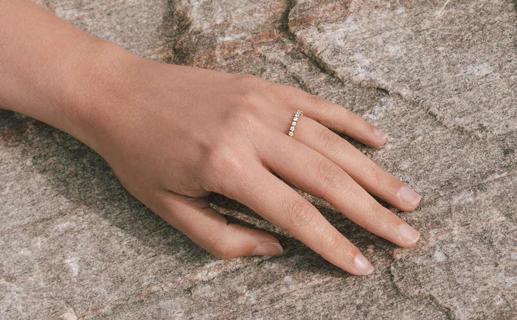 Eternity Ring rundrum mit Labordiamanten besetzt glänzt an Hand einer Frau