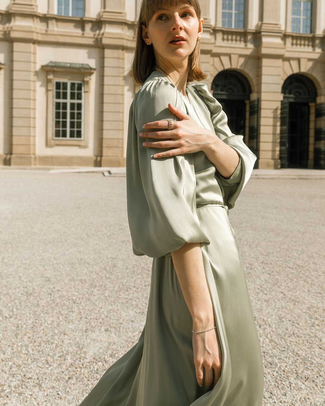 Model in einem Schlossinnenhof im grünen Kleid trägt den nachhaltigen Schmuck von Maren Jewellery aus recyceltem Gold und Labordiamanten
