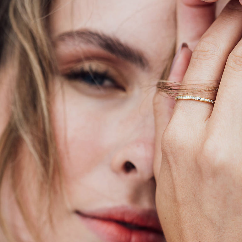 Feiner schlichter Ring aus recyceltem Gold mit Labordiamanten rundherum gefasst von Maren Jewellery an der Hand eines Models, das verträumt in die Kamera schaut