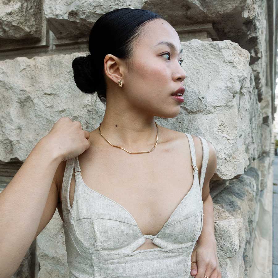 Frau mit hochertigem Designer Gold Schmuck Stabkette und Ohrring