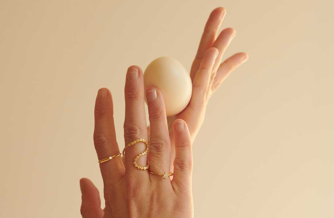 Hand mit vielen Designer Ringen aus recyceltem Gold