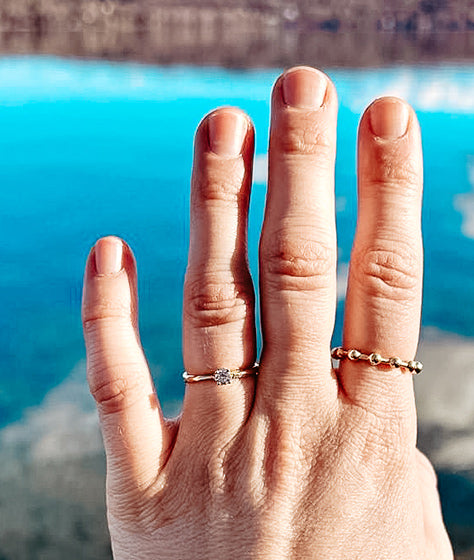 Hand mit Ringen vor Seepanorama