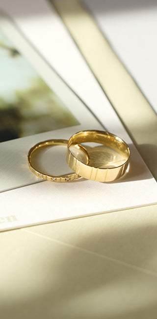 Detailaufnahme von in Handarbeit hergestellten Eheringen aus recyceltem Gold in sanftem Sonnenicht