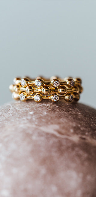 Nahaufnahme von gestapelten Kugelringen aus recyceltem Gold und Labordiamanten, die langsam und bewusst von Maren Jewellery gefertigt wurden.