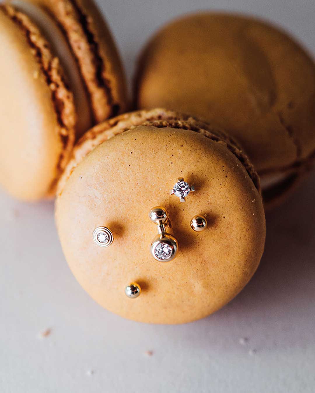 Luxuriöse und nachhaltige Ohr Piercing Stecker von Maren Jewellery die in ein Macaron gesteckt sind