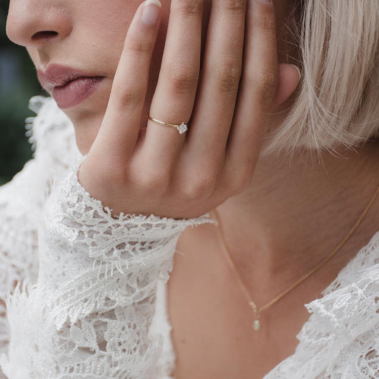 Klassischer Solitaire Verlobungsring aus recyceltem Gold und Labordiamant von Maren Jewellery an der Hand eines Models im weißen Spitzenkleid
