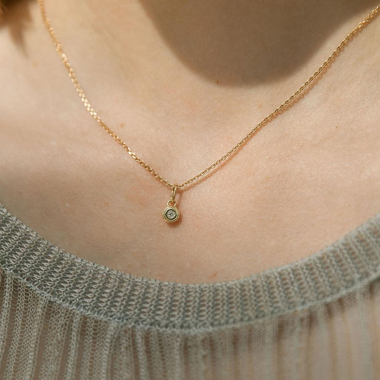 Mini Anhänger aus recyceltem Gold und mit Labordiamant besetzt von Maren Jewellery an einer Kette um den Hals eines Models im Sonnenschein
