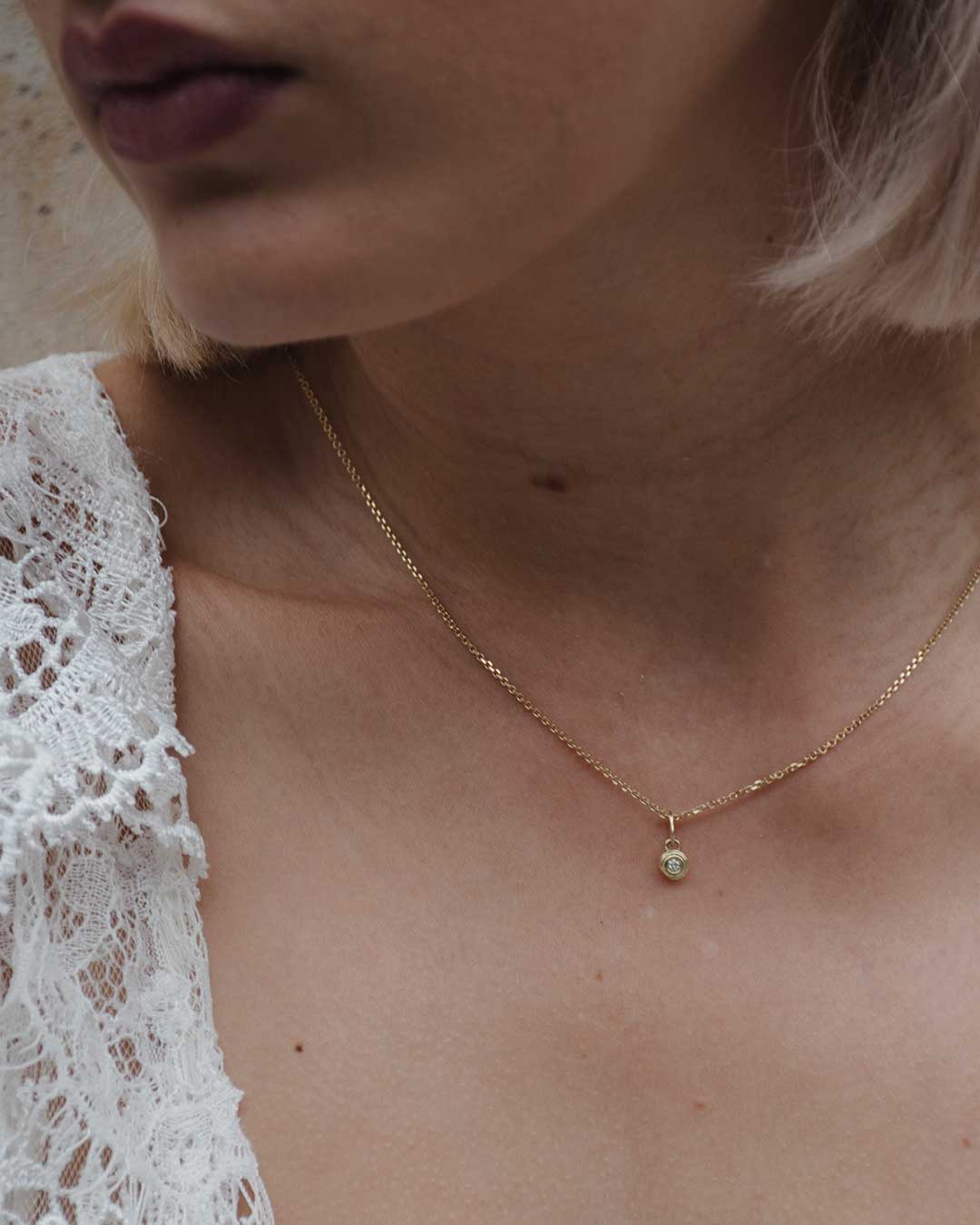 Detailaufnahme eines Models, die eine Goldkette mit klassischem Minianhänger mit Labordiamant aus recyceltem Gold trägt