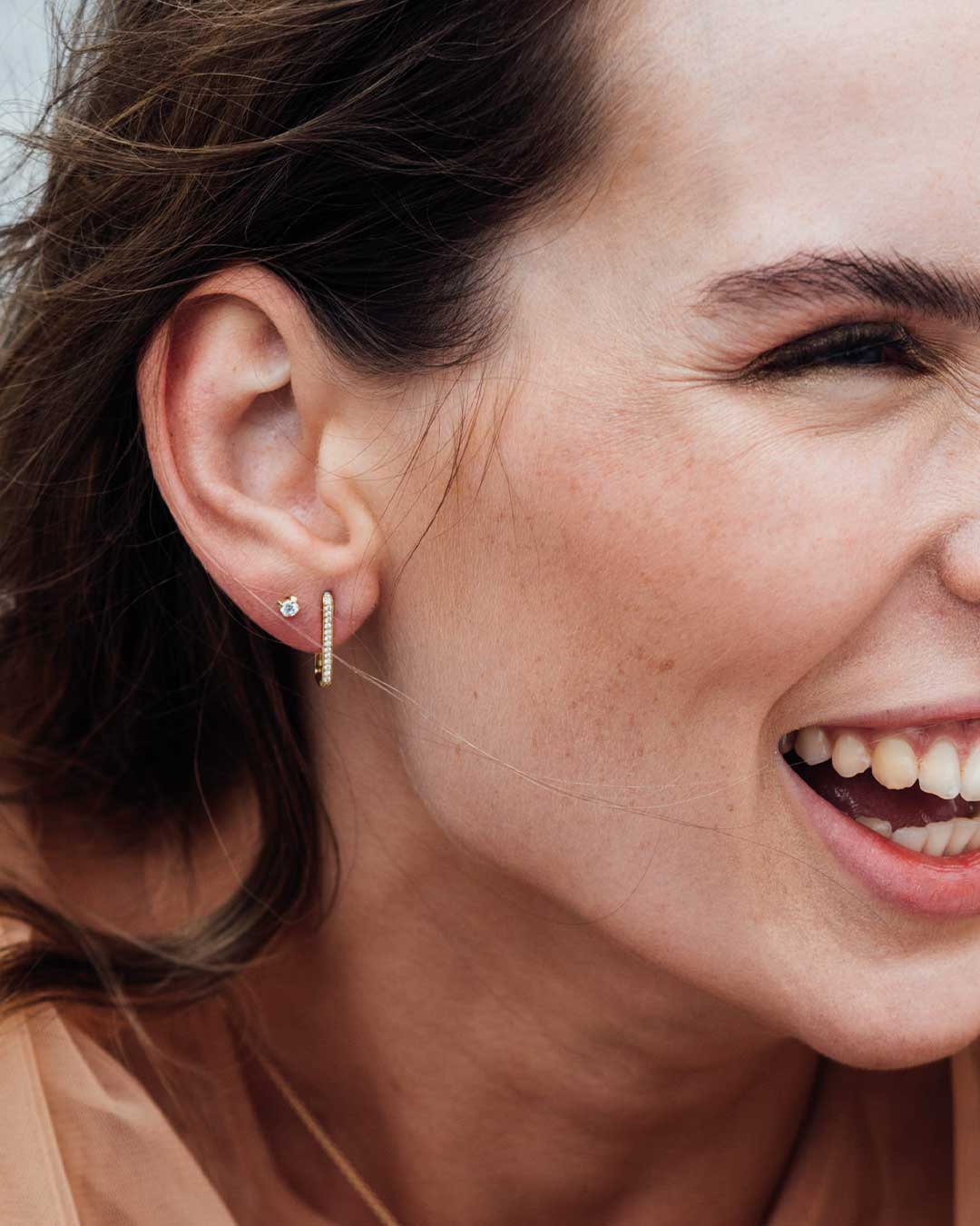 Nachhaltige Ohrstecker von Maren Jewellery aus recyeltem Gold am Ohr  eines lachenden Models