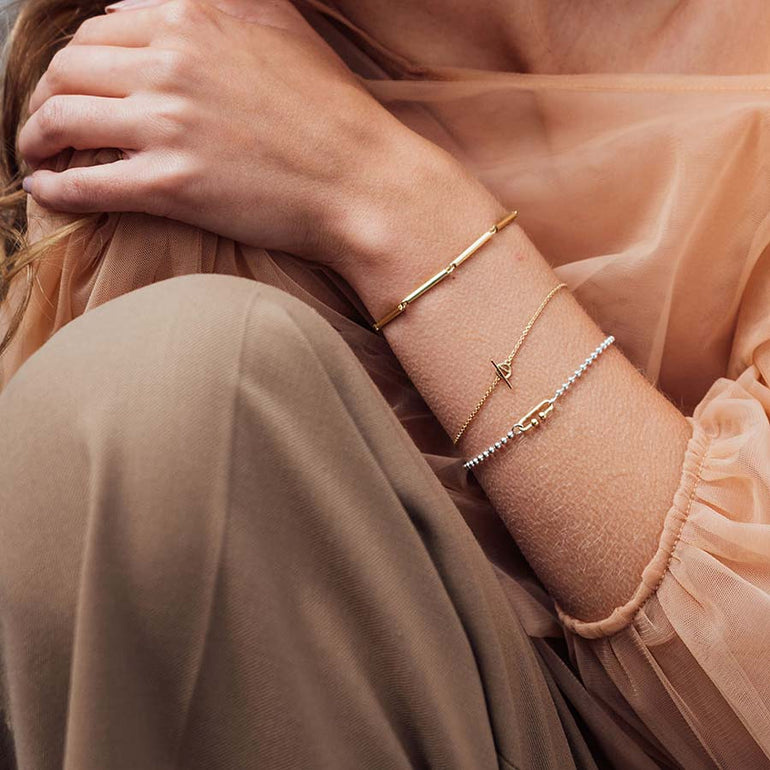 Arm mit drei minimalistischen Designer Armbänder aus recyceltem Gold