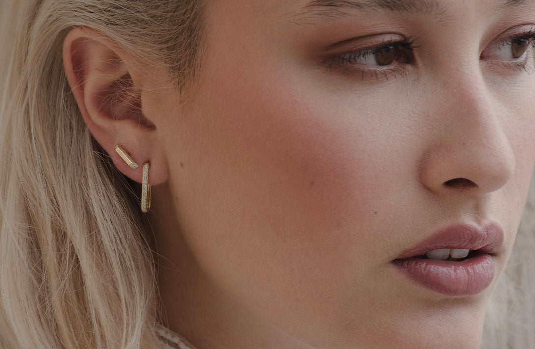 Nahaufnahme zeigt das feine Gesicht eines Models, ds verträumt zur Seite blickt und dabei die nachhaltigen Ohrstecker von Maren Jewellery an ihrem Ohr präsentiert