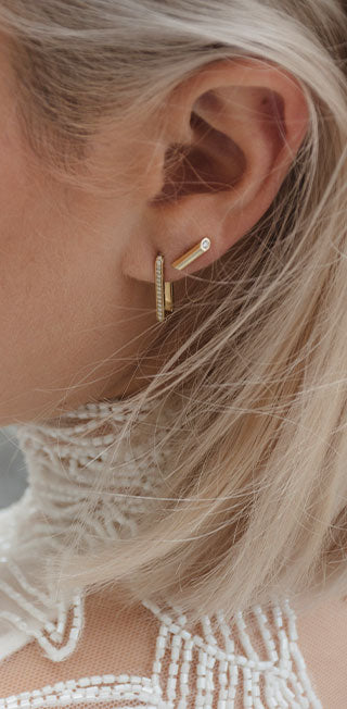 Nahaufnahme zeigt das Ohr eines Models im Hochzeitskleid, das mit nachhaltigen Ohrringen passend zur Hochzeit geschmückt ist
