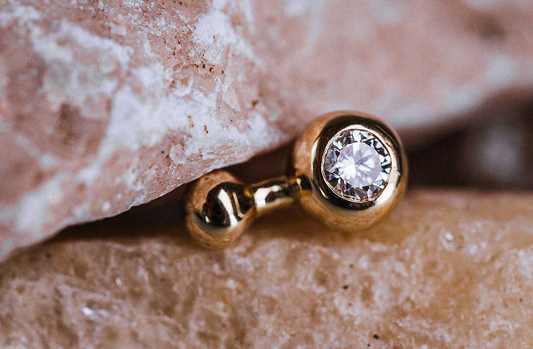 Nahaufnahme eines nachhaltigen Ohrsteckers von Maren Jewellery, der kunstvoll in einer Felsspalte steckt