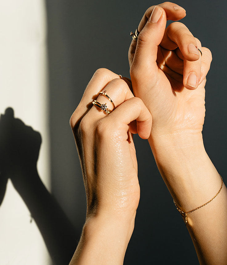 Hände mit nachhaltigem Goldschmuck im Licht-Schattenspiel