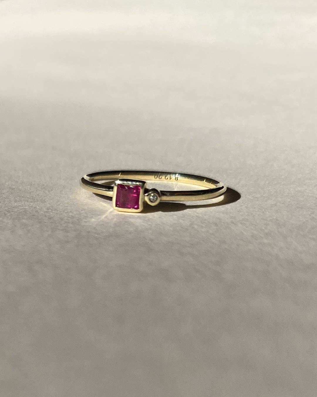 Goldring mit lila Diamant handwerklich von Maren Jewellery hergestellt liegt auf grauem Untergrund und strahlt im Sonnenlicht