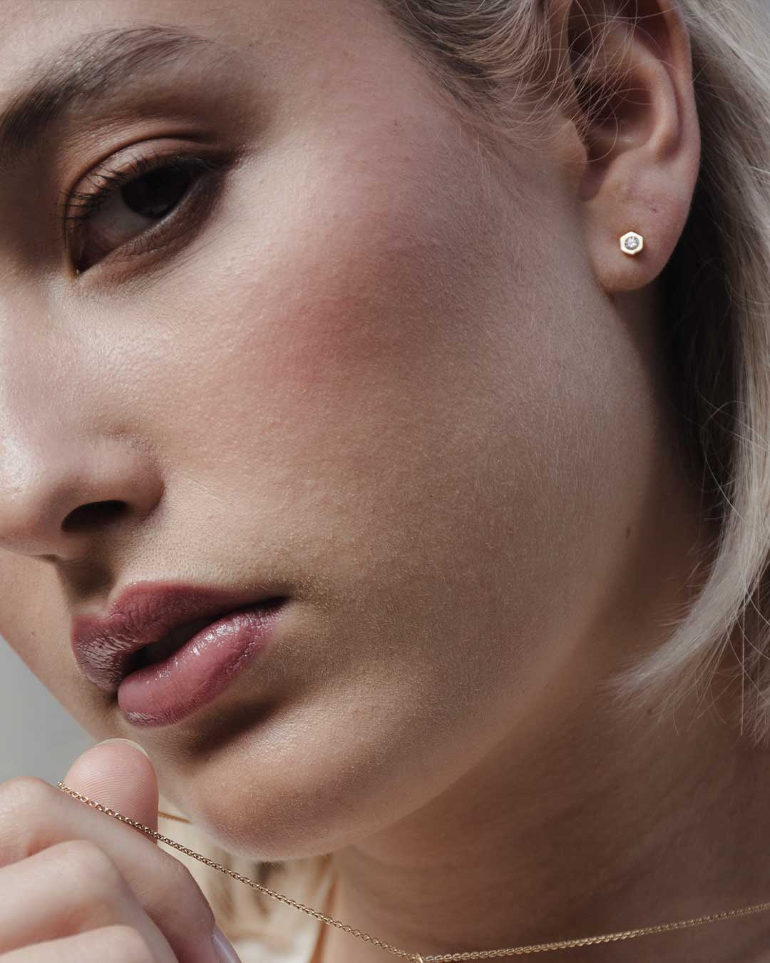 Potrait eines Models mit Fokus auf den nachhaltigen Designer Ohrstecker von Maren Jewellery aus recyceltem Gold mit Labordiamant