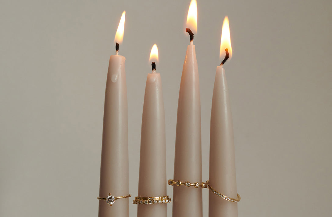 4 brennende Stabkerzen mit aufgesteckten Ringen aus recyceltem Gold und Labordiamanten von Maren Jewellery