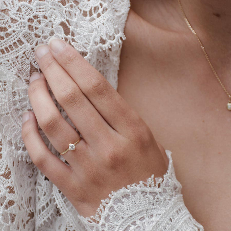 Verlobungsring aus recyceltem Gold mit Labordiamant besetzt von Maren Jewellery an der Hand eines Models im weißen Kleid