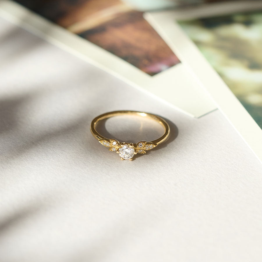 Ein mit Labor Diamanten besetzer Verlobungsring aus recyceltem Gold mit einem zarten Blütenmuster