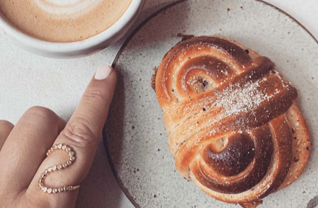 Hand mit Wellenring im Cafe mit Zimtschnecke