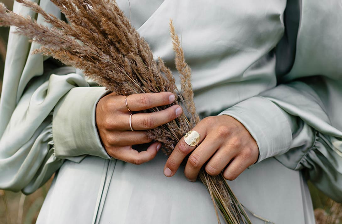 Junges Model mit Gräser Strauß in den Händen trägt den nachhaltigen Designer Schmuck aus der Wilderness Kollektion von Maren Jewellery