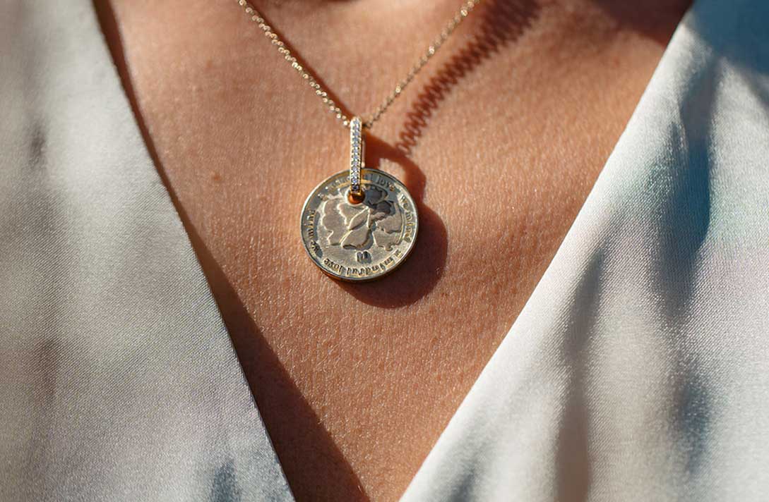 Wildflowers Münzanhänger aus recyceltem Gold und Labordiamanten von  Maren Jewellery als Talisman an der Halskette eines Models im Sonnenschein