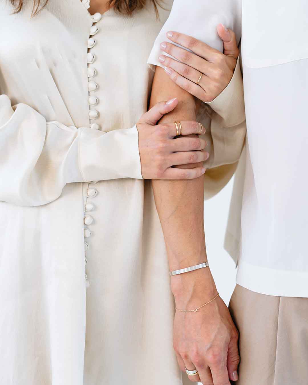 Bildausschnitt zeigt eine Frau, die sich an ihrem Partner festhält; beide sind elegant schlicht gekleidet und tragen nachhaltigen Schmuck von Maren Jewellery