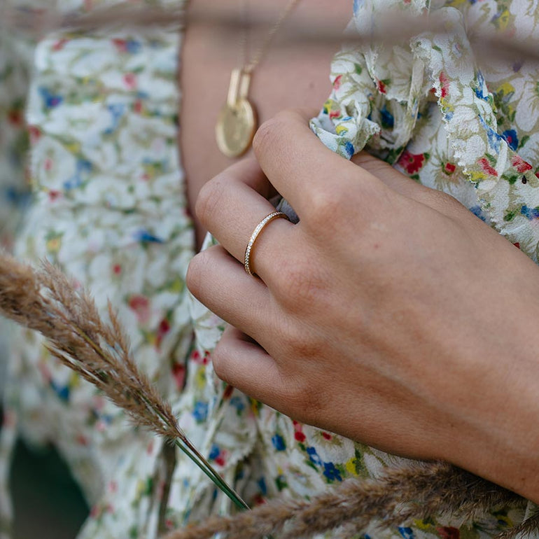 Zarter Bandring aus recyceltem Gold ringsherum mit Labordiamanten besetzt von Maren Jewellery an der Hand eines Models im Blumenkleid