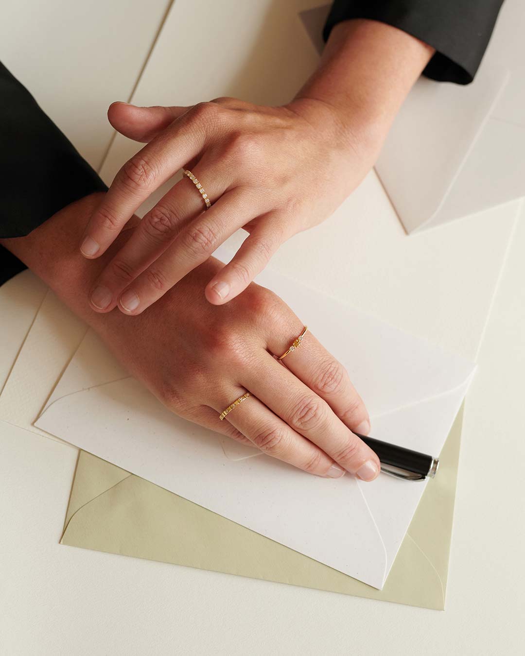 Elegante Frauenhände geschmückt mit nachhaltigen Ringen von Maren Jewellery über Stift und Briefpapier
